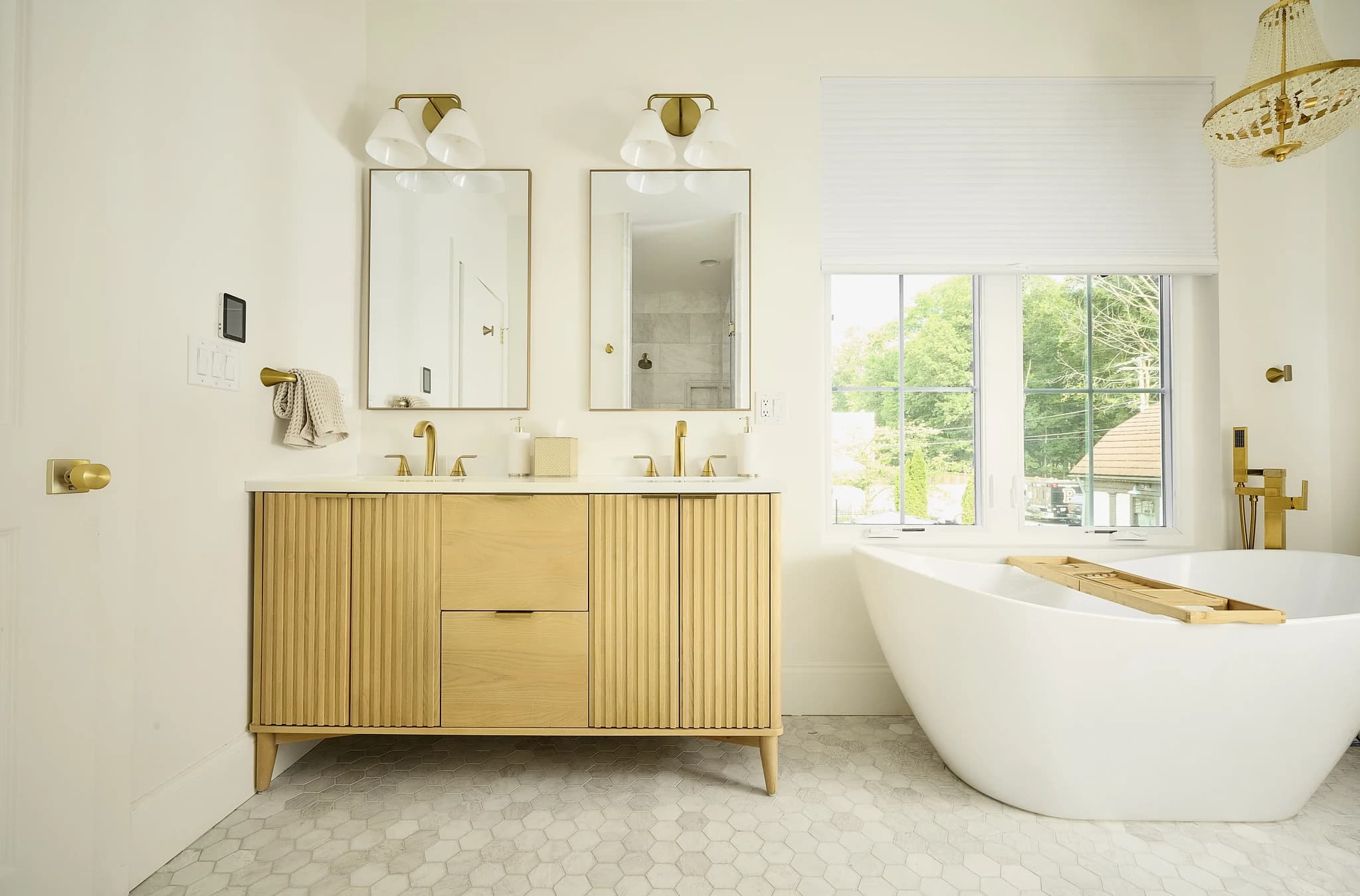 Primary bathroom with a freestanding tub, double vanity, and warm brass fixtures in Meridian-Kessler.